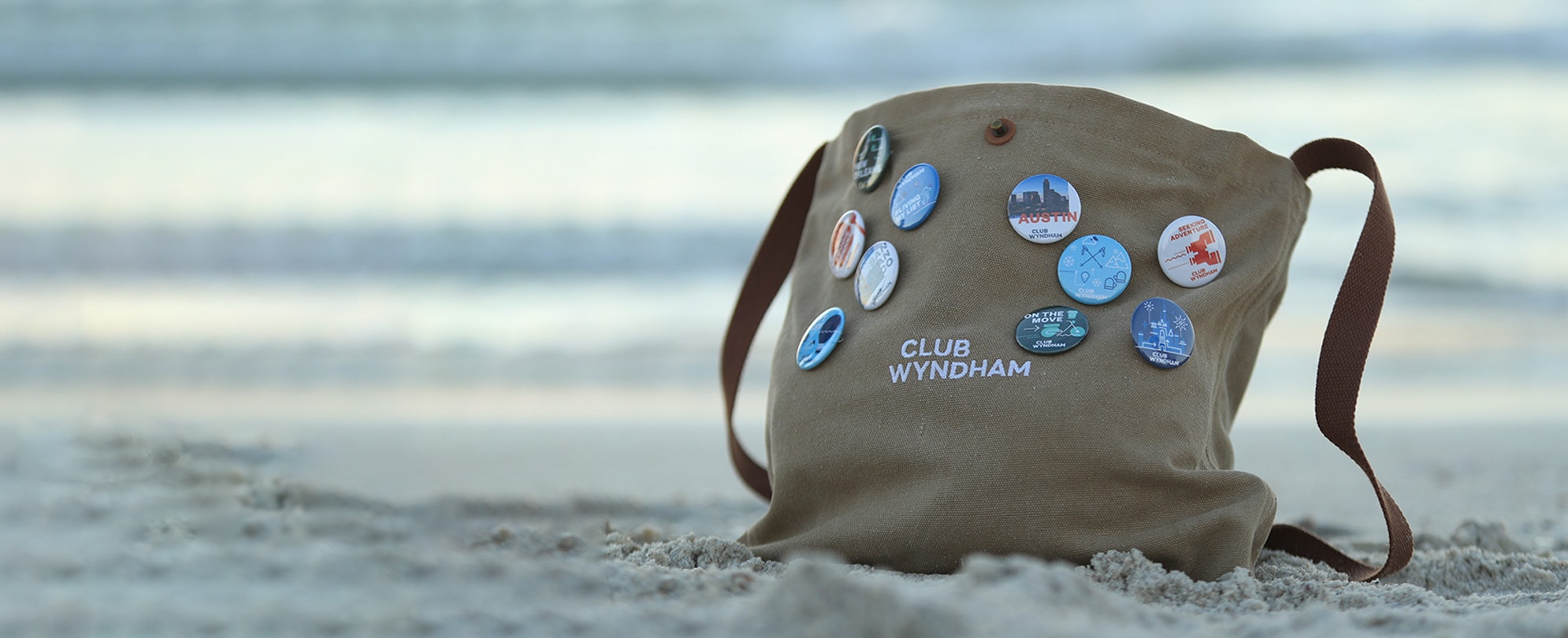 A club Wyndham canvas bag with ten pins is in the sand on a beach.