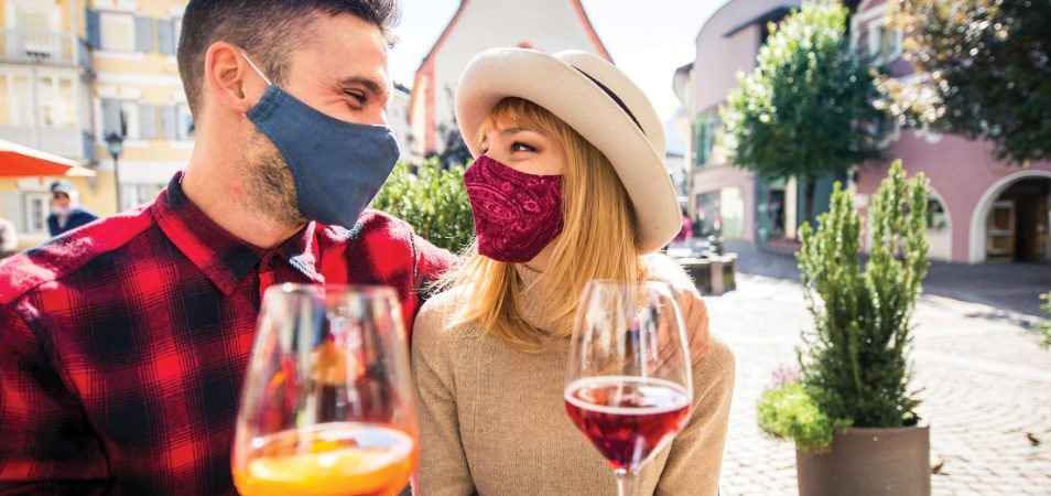 Masked man and woman drinking wine in a top drinking destination